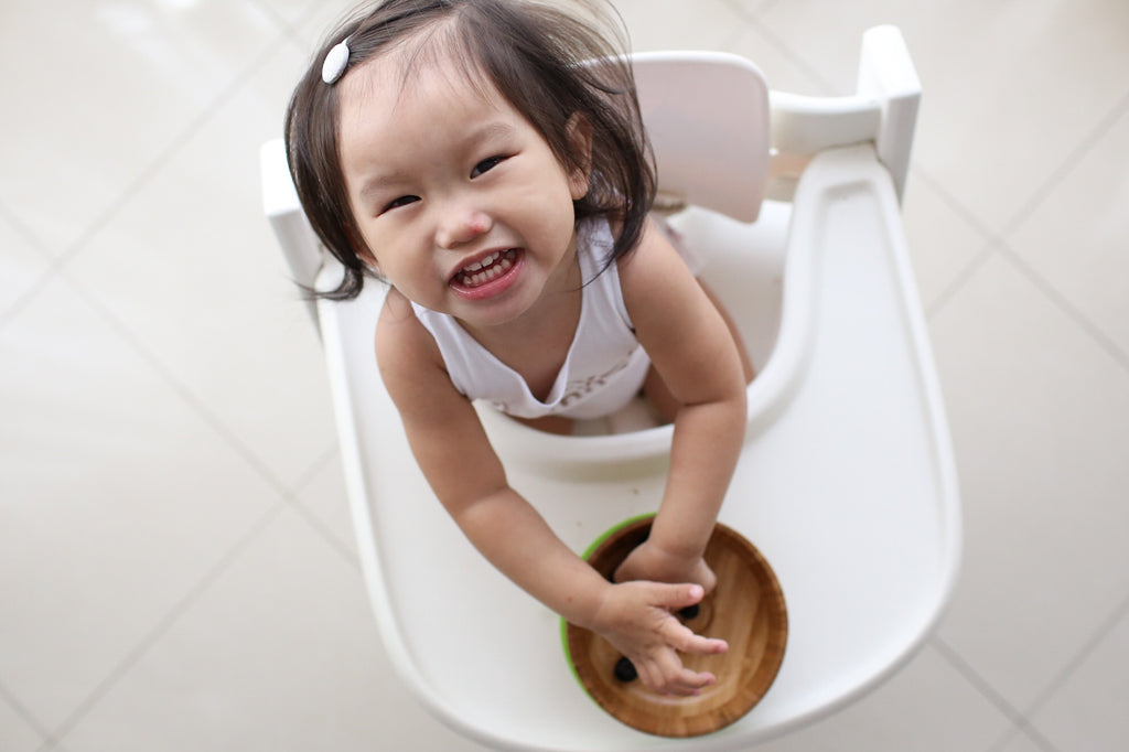 Girl in high chair eating from bamboo bowl Emondo Kids